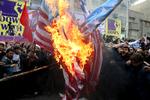 Iranske demonstranter brænder rituelt det amerikanske flag foran USAs tidligere ambassade i Teheran,

 Foto: Vs Mma**cai**/AP