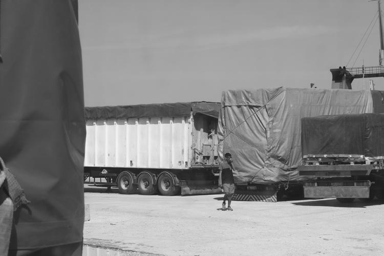 En menneskesmugler står på havnen på Lesbos. Bag ham er en flygtning ved at stige ombord på lastbilen, der skal fragte ham til europæisk fastland. Foto: Nadim Ghaderi