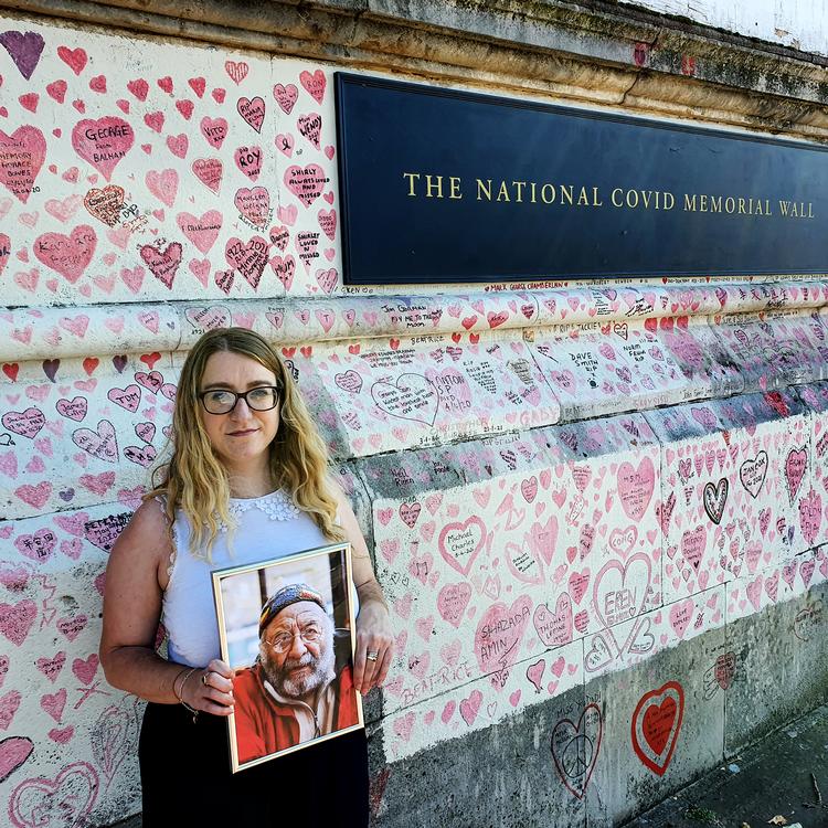 Jo Goodman med et billede af sin far ved coronamindesmuren i London. Foto: Nilas Heinskou