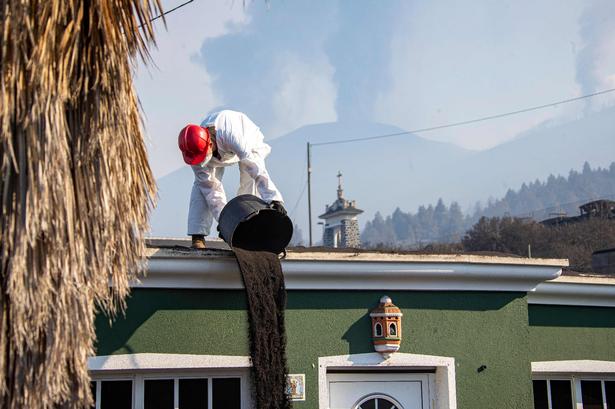 Aske fjernes fra et bygningstag.  Foto: Luismi Ortiz/Ritzau Scanpix