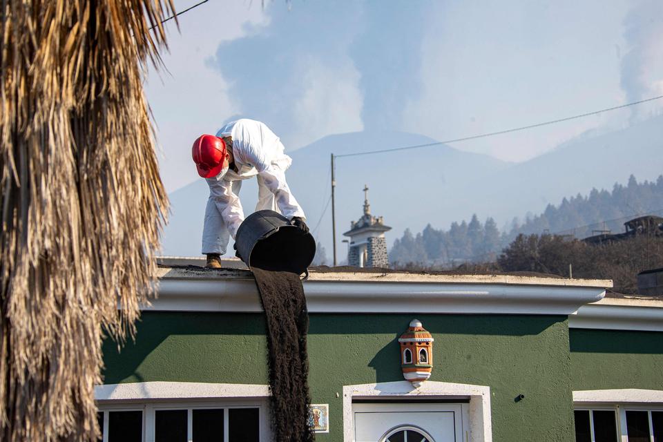 Aske fjernes fra et bygningstag.  Foto: Luismi Ortiz/Ritzau Scanpix