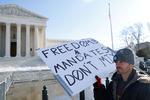 En demonstrant står uden for det amerikanske højesteret i Washington. Netop spørgsmålet om vaccinekrav splitter politikerne.     Foto: Jonathan Ernst/Ritzau Scanpix