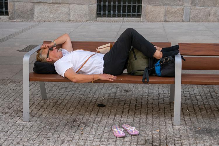 En kvinde ligger på en bænk i Madrid i august 2021, da en hedebølge fik termometeret op på 46 grader. Foto: Andrea Comas/Ritzau Scanpix