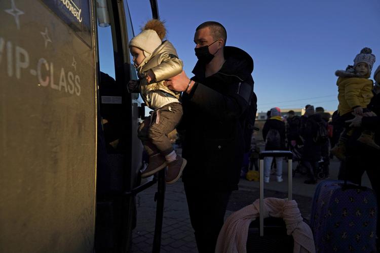 En baby, hvis familie netop er flygtet fra invasionen i Ukraine, bliver løftet ind i en bus i Medyka, Polen for at blive kørt væk fra grænsen. Foto: Bryan Woolston/Ritzau Scanpix