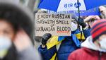 'Nyd russisk gas sammen med lugten af ukrainsk blod', står der på banneret, som en demonstrant holder foran den tyske regeringsbygning i Berlin i dag.  Foto: John Macdougall/Ritzau Scanpix