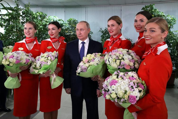 Når han har mødtes med europæiske regeringsledere som Emmanuel Macron eller Olaf Scholz, har Vladimir Putin holdt god afstand. Da den russiske præsident lørdag besøgte et træningscenter for piloter, stod han anderledes tæt med stewardesserne fra luftfartsselskabet Aeroflot. Foto: Sputnik/Ritzau Scanpix