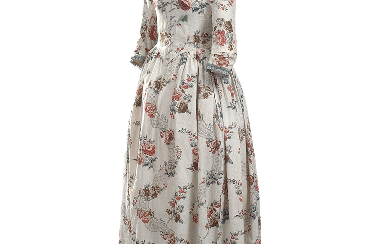 Engelsk kjole, 1780’erne. »Kjolen er et udtryk for den nye friluftsagtige mode. Den er i bomuld, et koloniprodukt, som kan spindes og væves i Manchesters store industri, og mønsteret er ikke broderet, men trykt, så det er relativt billigt. Kjolen kan snøres foran, så man behøver ikke have en kammerpige. Det er en nem kjole. Man bærer godt nok stadig korset under, men den er ikke selv stivet, og man har kun få skørter under og ingen stivere. Det er en kjole, man kan begynde at spadsere i og bevæge sig i. Det er begyndelsen på det bekvemme tøj. Stilen kaldte man i tiden engelsk, fordi den blev kædet sammen med landgodserne og det parlamentariske England fremfor det mere stive, enevældige franske hof«. MVP Foto: Nationalmuseet. Foto Roberto Fortuna og Peter Danstrøm