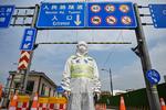 En trafikmedarbejder iført beskyttelsesudstyr fra top til to regulerer adgangen til en tunnel i Kinas største by Shanghai, der er ramt af en lockdown, hvor hele byen skal testes. Foto: Hector Retamal/Ritzau Scanpix