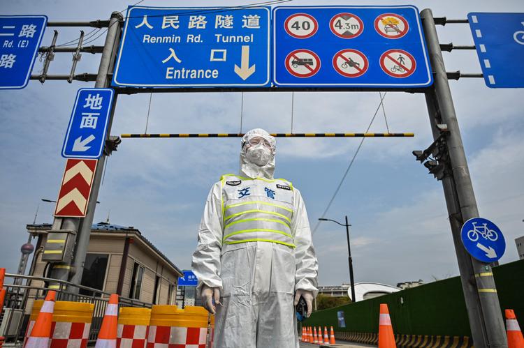En trafikmedarbejder iført beskyttelsesudstyr fra top til to regulerer adgangen til en tunnel i Kinas største by Shanghai, der er ramt af en lockdown, hvor hele byen skal testes. Foto: Hector Retamal/Ritzau Scanpix
