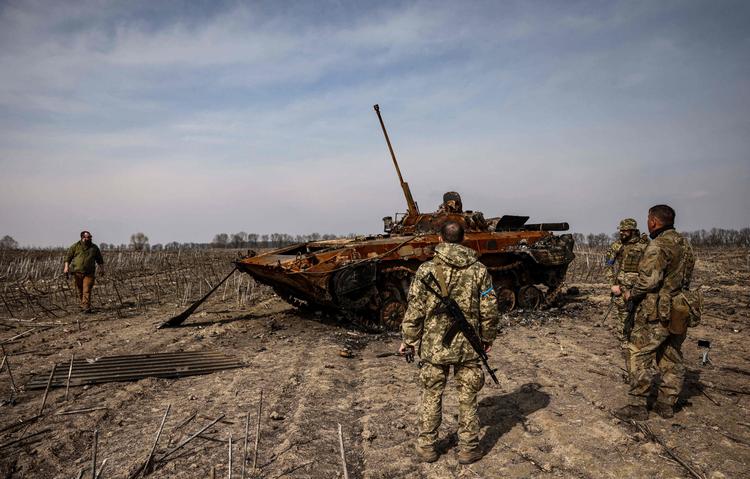 Ukrainske soldater samles om en udbrændt russisk kampvogn uden for Kyiv torsdag. Ifølge en amerikansk tænketank er Rusland de seneste dage trængt tilbage i området ved hovedstaden.  Foto: Ronaldo Schemidt/Ritzau Scanpix