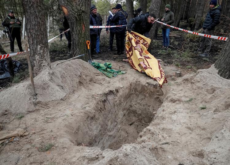 En mand dækker kroppen på en afdød kvinde, som angiveligt blev dræbt af russiske soldater i landsbyen Motyzjyn. Det er et af flere lig, som indbyggerne ifølge Reuters har fundet. 4. april 2022. Foto: Gleb Garanich/Ritzau Scanpix