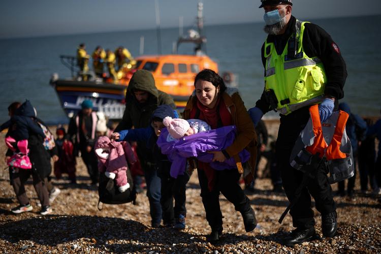 Ifølge BBC krydsede 28.526 migranter i 2021 Den Engelske Kanal i håb om en bedre tilværelse i Storbritannien. Står det til Boris Johnson, skal de fremover flyves til Rwanda, mens de afventer deres asylbehandling, skriver Reuters. Her ses en gruppe migranter efter at være blevet ledsaget i land ved Dungeness af nødhjælpsorganisationen Royal National Lifeboat Institution. Foto: Henry Nicholls/Ritzau Scanpix