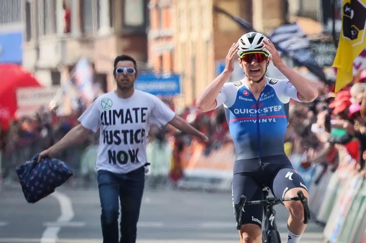 Mens Remco  Evenepoel længst havde lagt samtlige rivaler i Liège-Bastogne-Liège bag sig, blev han fulgt de sidste meter til målstregen af en klimaaktivitist, uden at det spolerede den 22-årige belgiers begejstring over triumfen.
 Foto: Benoit Doppagne/Ritzau Scanpix