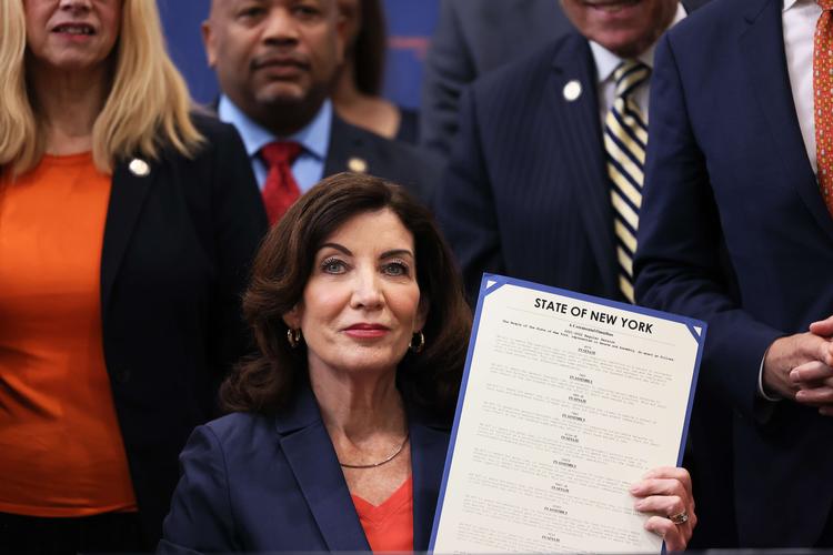 NEW YORK, NEW YORK - JUNE 06: Gov. Kathy Hochul holds up signed legislation as she is surrounded by lawmakers during a bill signing ceremony at the Northeast Bronx YMCA on June 06, 2022 in New York City. Gov. Hochul signed a series of gun reform bills, that will strengthen already strict gun laws in the state. Passed by lawmakers last week, one restriction includes banning anyone under age 21 from buying or possessing a semi-automatic rifle, among a series of other changes. The bills were passed in the wake of two recent mass shootings where an 18-year-old man fatally shot 10 people and injured 3 in Buffalo, New York and just 10 days later an 18-year old man shot and killed 19 children and 2 adults at an elementary school in Uvalde, Texas. Michael M. Santiago/Getty Images/AFP == FOR NEWSPAPERS, INTERNET, TELCOS &amp; TELEVISION USE ONLY == Foto: Michael M. Santiago/Ritzau Scanpix