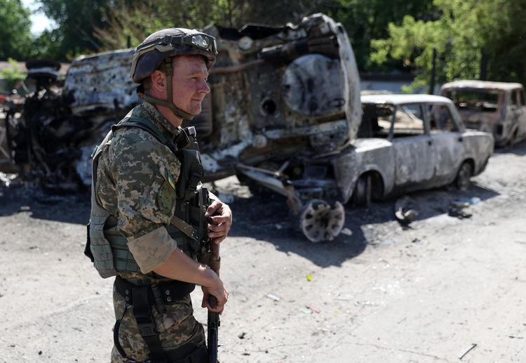  En ukrainsk soldat i Lysytjansk passerer et par bilvrag.  Foto: Anatolii Stepanov/Ritzau Scanpix