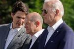 Canadas premierminister, Justin Trudeau, hvisker Tysklands kansler, Olaf Scholz, i øret, mens USA's præsident ser ud til at passe sig selv.  Foto: Jonathan Ernst/Ritzau Scanpix