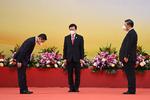 En embedsmand bukker for Kinas præsident Xi Jinping (højre) og John Lee (midte), under Lees indsættelsesceremoni. Foto: Selim Chtayti/Ritzau Scanpix