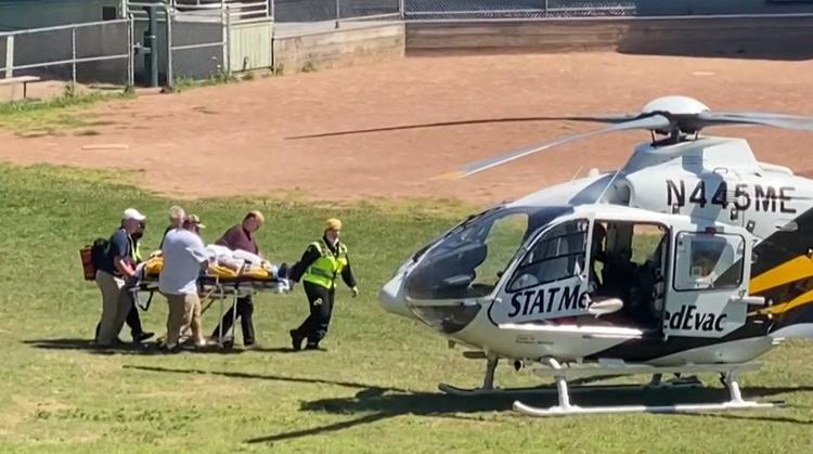 Salman Rushdie på vej til helikopteren, som bragte ham på hospitalet, hvor han blev lagt i respirator efter talrige knivstik. I weekenden kom han ud af respiratoren og han skal ifølge sin agent være i stand til at tale.  Foto: Horatio Gates/Ritzau Scanpix