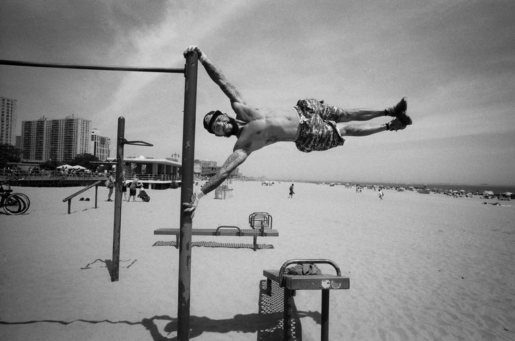 Man Elevated and Parallel to the EarthMandatory credit: Coney Island People 50 Years, 1970-2020 by Harvey Stein is published by Schiffer. The photographs are copyright Harvey Stein.Please include the following links:https://www.harveysteinphoto.com/coney-island-people-50-years-bookhttps://schifferbooks.com/collections/schiffer/products/coney-island-people?_pos=1&amp;_sid=fa06a2f4d&amp;_ss=r Foto: Coney Island People 50 Years, 1970-2020 by Harvey Stein is published by Schiffer. The photographs are copyright Harvey Stein.