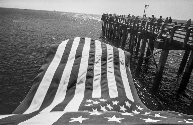 American Flag and PierMandatory credit: Coney Island People 50 Years, 1970-2020 by Harvey Stein is published by Schiffer. The photographs are copyright Harvey Stein.Please include the following links:https://www.harveysteinphoto.com/coney-island-people-50-years-bookhttps://schifferbooks.com/collections/schiffer/products/coney-island-people?_pos=1&amp;_sid=fa06a2f4d&amp;_ss=r Foto: Coney Island People 50 Years, 1970-2020 by Harvey Stein is published by Schiffer. The photographs are copyright Harvey Stein.