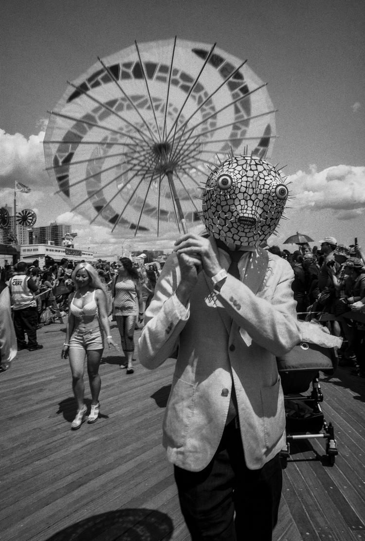 En mand med solparasol og kuglefiskemaske fordi... ja, det hensvæver lidt o tågerne.  Foto: Coney Island People 50 Years, 1970-2020 by Harvey Stein is published by Schiffer. The photographs are copyright Harvey Stein.