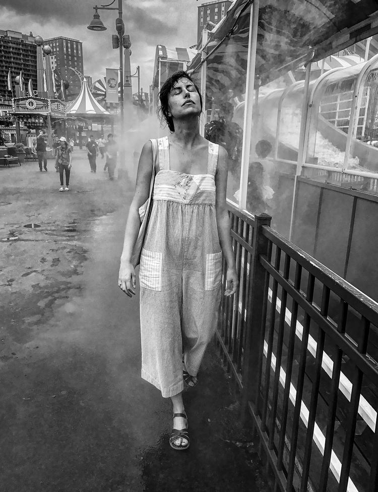 Woman Walking Through Water Spray Mandatory credit: Coney Island People 50 Years, 1970-2020 by Harvey Stein is published by Schiffer. The photographs are copyright Harvey Stein.Please include the following links:https://www.harveysteinphoto.com/coney-island-people-50-years-bookhttps://schifferbooks.com/collections/schiffer/products/coney-island-people?_pos=1&amp;_sid=fa06a2f4d&amp;_ss=r Foto: Coney Island People 50 Years, 1970-2020 by Harvey Stein is published by Schiffer. The photographs are copyright Harvey Stein.