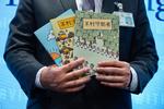 En politichef i Hongkong fremviser de tre børnebøger, som beskyldes for at være samfundsundergravende litteratur.  Foto: Vincent Yu/Ritzau Scanpix