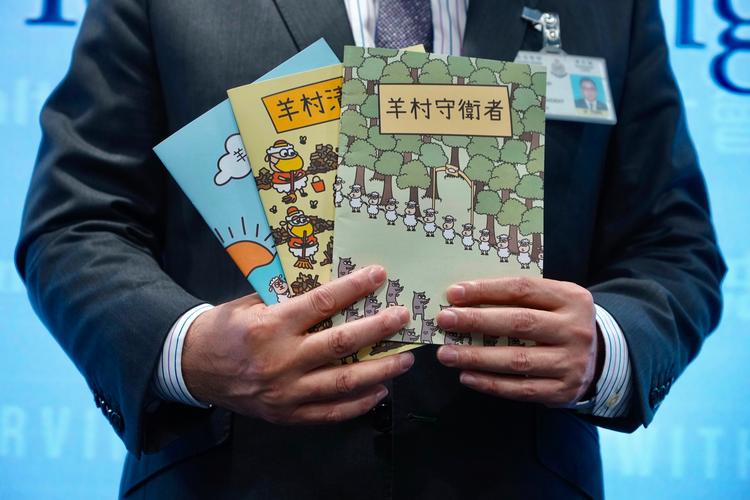 En politichef i Hongkong fremviser de tre børnebøger, som beskyldes for at være samfundsundergravende litteratur.  Foto: Vincent Yu/Ritzau Scanpix
