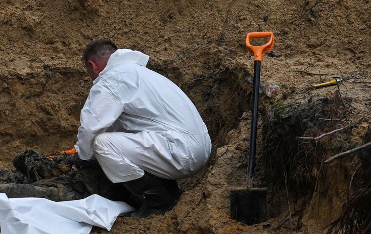    En ukrainsk tekniker undersøger et lig i en massekrav i Ukraine torsdag. Disse fund vil styrke presset på Rusland og krav om at stille præsident Putin for Den Internationale Straffedomstol - som hverken Rusland eller USA anerkender. Foto: Juan Barreto/Ritzau Scanpix