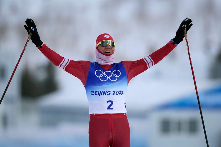 Russiske Alexander Bolshunov i mål efter 50 km langrend ved vinter-OL i Beijing, der kun kunne lade sig gøre på grund af snekanoner og kunstsne.  Foto: Aaron Favila/Ritzau Scanpix
