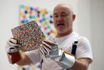 Den britiske kunstner Damien Hirst med et af de omtalte malerier i hænderne. Foto: Hannah Mckay/Ritzau Scanpix