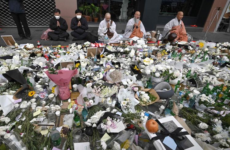 Buddhistiske munke beder for ofrene fra Halloween-tragedien, hvor forbipasserende lægger breve, blomster og offergaver. Foto: Jung Yeon-je/Ritzau Scanpix
