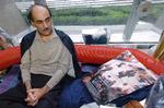 Mehran Karimi Nasseri fotograferet i 2004 i Charles de Gaulle-lufthavnen i Paris, mens han kigger på en plakat med den film, hans liv dannede grundlaget for.  Foto: Stephane De Sakutin/Ritzau Scanpix