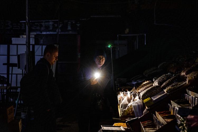 En butiksejer hjælper en kunde med at finde varer i Kyiv, som er et af de mange steder i Ukraine, hvor indbyggerne er uden strøm. Foto: Dimitar Dilkoff/Ritzau Scanpix