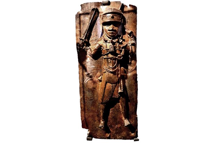 Dette relief af en bevæbnet kriger befandt sig indtil de britiske plyndringer i 1897 i paladset i kongedømmet Benin. Via kunsthandleren Willian Downing Webster endte det to år efter på National Museet i København, hvor det har været siden.  