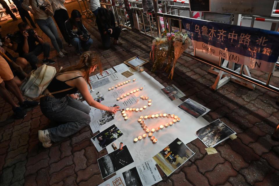 Demonstranter i Hongkong skriver 1124 med lys. Tallene henviser til den dato, hvor 10 personer blev dræbt i en brænd i byen Urumqi i Kina, fordi de på grund af coronarestiktioner var låst inde af myndighederne.  Foto: Peter Parks/Ritzau Scanpix