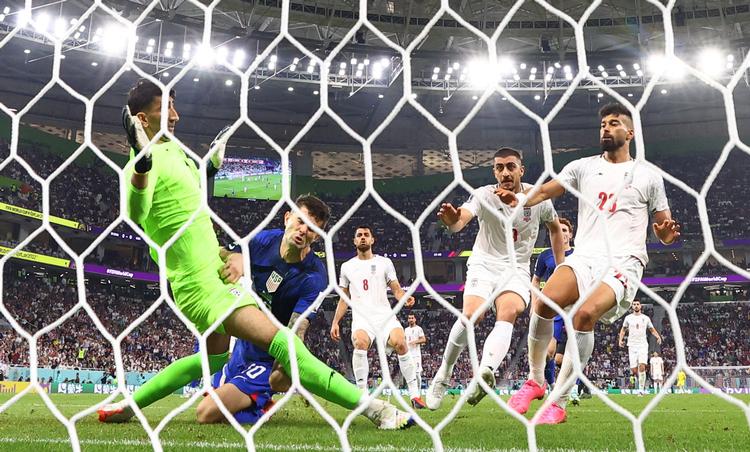 USA's Christian Pulisic (blå), der til daglig spiller for Chelsea i Premier League, scorede sikkert i tirsdag aftens opgør mod Iran, men han blev skadet ved aktionen, da han stødte ind i den iranske målmand Alireza Beiranvand.  Foto: Kai Pfaffenbach/Ritzau Scanpix