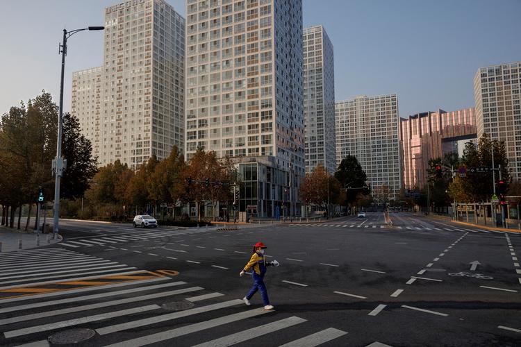 En kvinde krydser gaden under 'myldretiden' i Beijing. 23. november. Foto: Thomas Peter/Ritzau Scanpix