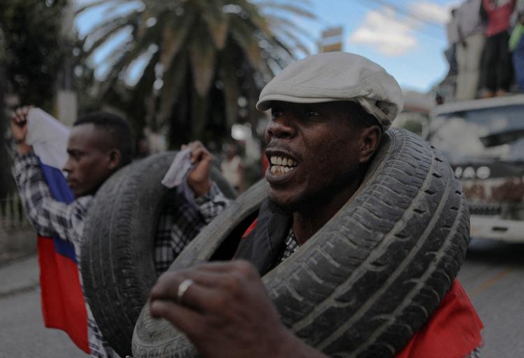 Mænd bærer bildæk som led i en demonstration mod de høje leveomkostninger og bandekriminaliteten i Haitis hovedstad, Port-au-Prince. Foto: Ralph Tedy Erol/Ritzau Scanpix