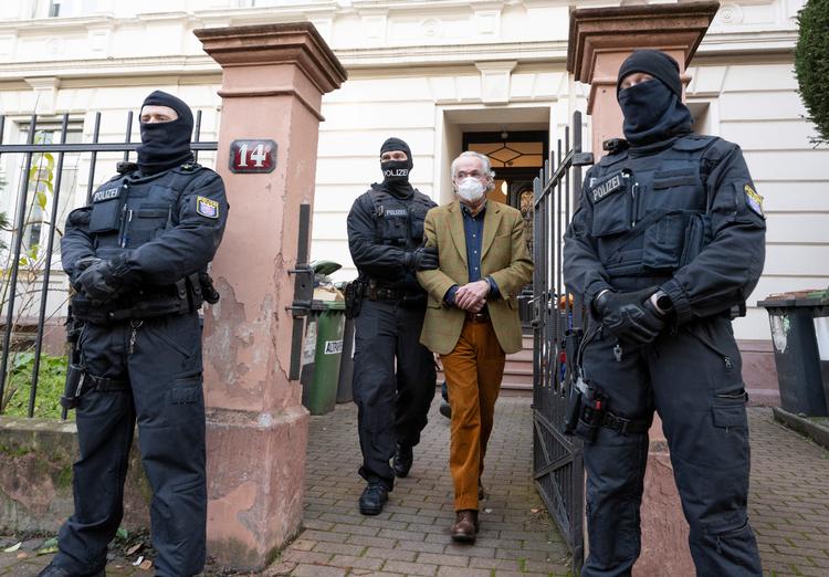 Under en razzia i den tyske delstat Hessen føres én af de formodede bagmænd, Heinrich Reuß, til en ventende politibil.  Foto: Boris Roessler/Ritzau Scanpix