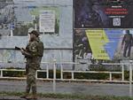 En ukrainsk politibetjent taler i telefon ved siden af en plakat, der opfordrer alle i Kherson til at fordømme personer, som kollaborerede med russerne. Foto: Genya Savilov/Ritzau Scanpix