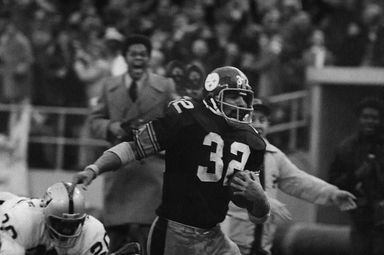 Pittsburgh Steelers-running back Franco Harris undviger her en tackling fra Oakland Raiders' Jimmy Warren på vej mod det afgørende 42-yard touchdown i slutspilskampen mod Oakland Raiders lillejuleaften 1972. Foto: Harry Cabluck/Ritzau Scanpix