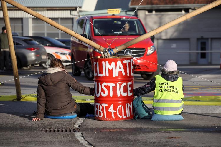    Davos-mødet åbnede mandag samtidig med Oxfam's rapport om voksende ulighed i verden. I Schweiz bød klimaaktivisterne de økonomiske og politiske topfolk i Davos velkommen med en demonstration.  Foto: Debt For Climate Switzerland/Ritzau Scanpix