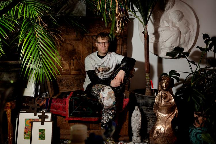 Alexander Tovborg sidder i sit studie i København på en kirkebænk fra starten af 1900-tallet. Det var jagten på kirkebænke til en ny udstilling, der satte gang i sagen om det falske maleri. Foto: Martin Lehmann