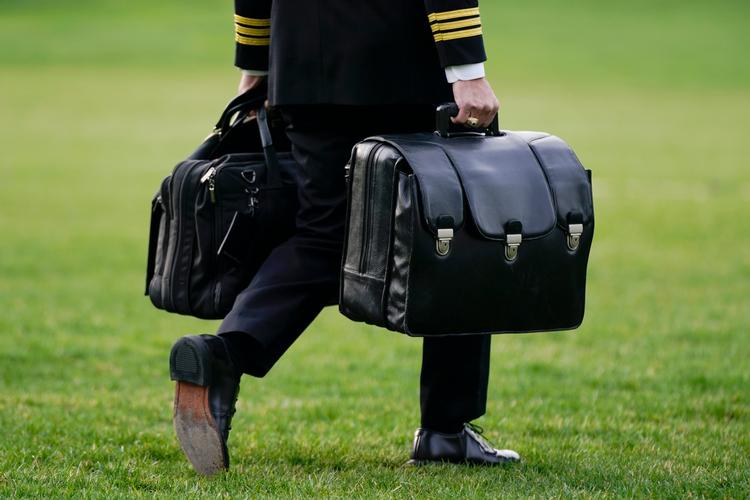 'Atom-fodbolden', en flere kilo tung, sort taske, der indeholder atomkoderne, bliver båret over Det Hvide Hus' 'South Lawn' af en fra militæret. (AP Photo/Patrick Semansky) Foto: Patrick Semansky/Ritzau Scanpix