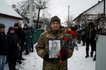  En ukrainsk soldat holder et billede af Volodymyr Androshchuk i forbindelse med den talentfulde tikæmpers begravelse i hjembyen, Letychiv. Foto: Valentyn Ogirenko/Ritzau Scanpix