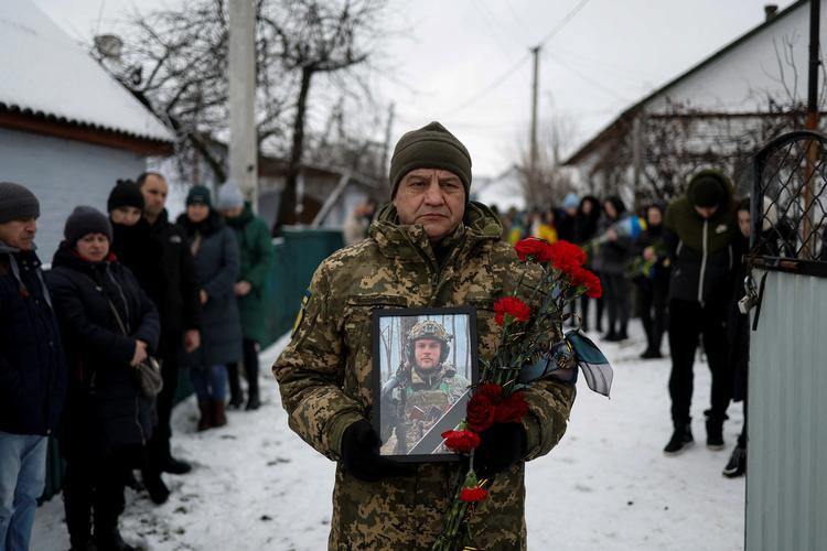  En ukrainsk soldat holder et billede af Volodymyr Androshchuk i forbindelse med den talentfulde tikæmpers begravelse i hjembyen, Letychiv. Foto: Valentyn Ogirenko/Ritzau Scanpix