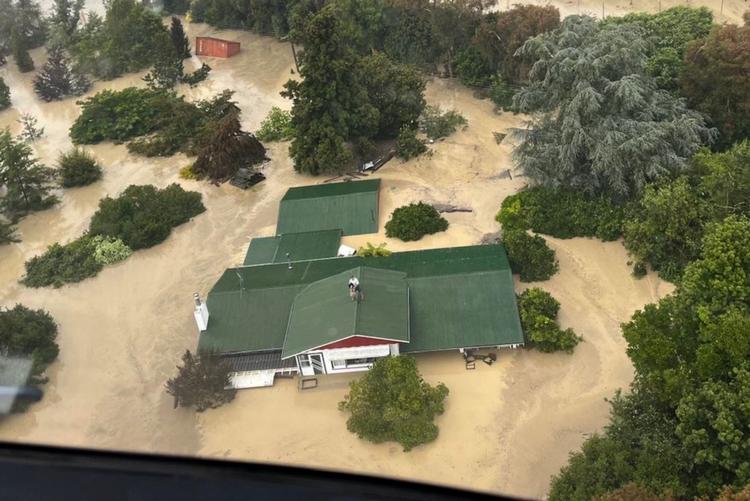 Oversvømmelserne er massive efter tyfonen Gabrielles hærgen i New Zealand. En familie måtte søge tilflugt på taget af deres hus nær byen Napier, før de kunne blive reddet af en helikopter. Foto: Handout/Ritzau Scanpix