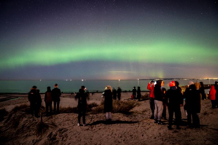 Mennesker forsamlet ved et flot nordlys på Hornbæk Strand ved Nordsjælland. Foto: Mads Claus Rasmussen/Ritzau Scanpix