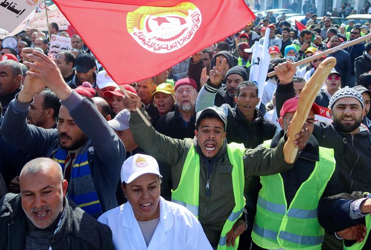 En demonstrant holder symbolsk et brød i vejret. Prisen på elementære fødevarer eksploderer, og præsidenten er rede til at stoppe statens tilskud til fødevarer. I dele af landet hersker reel sult. Foto: Jihed Abidellaoui/Ritzau Scanpix